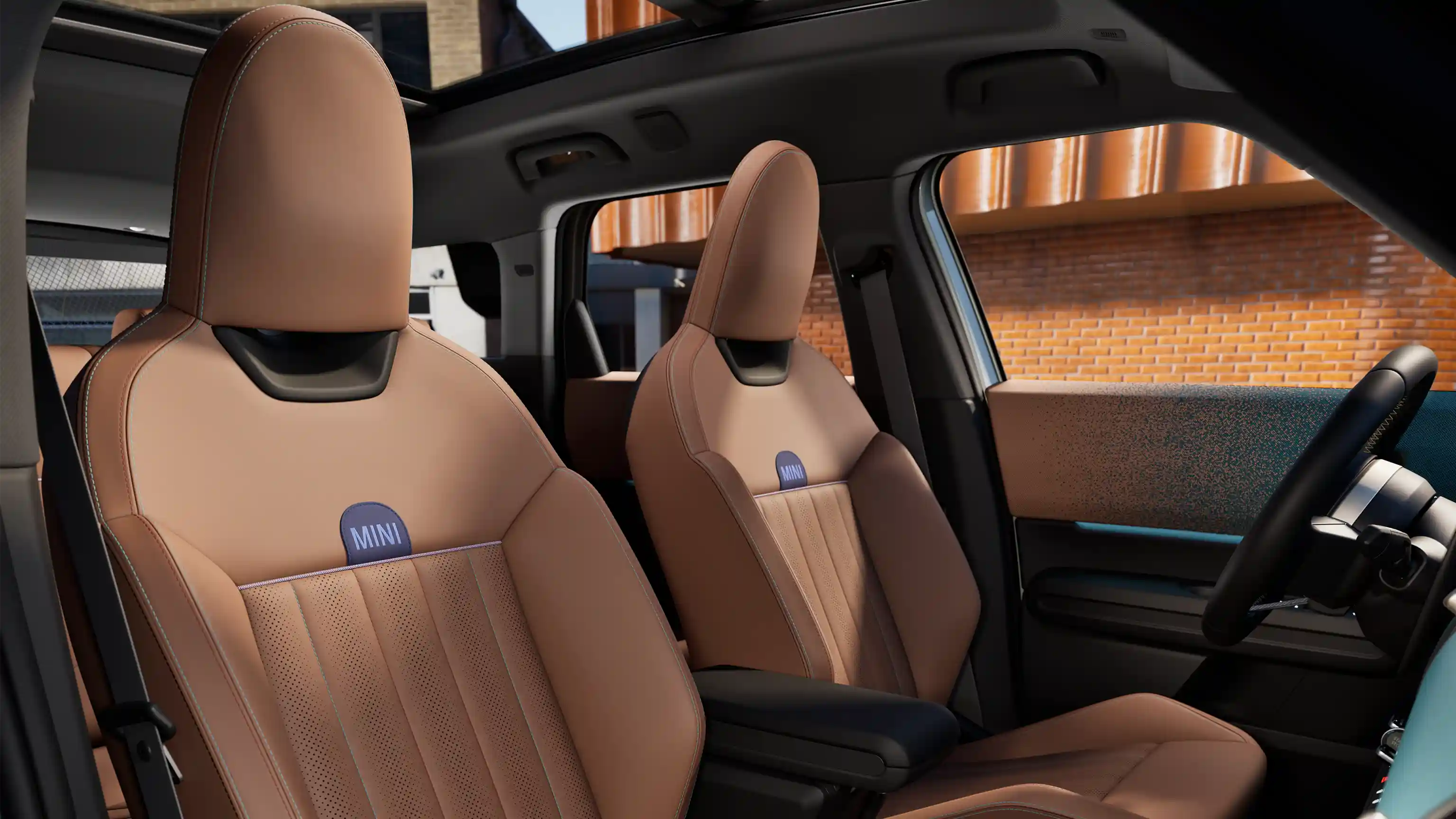 Interior perspective of the MINI Countryman is showing the dashboard, steering wheel, round display, panorama glassroof  and back of the frontseats.