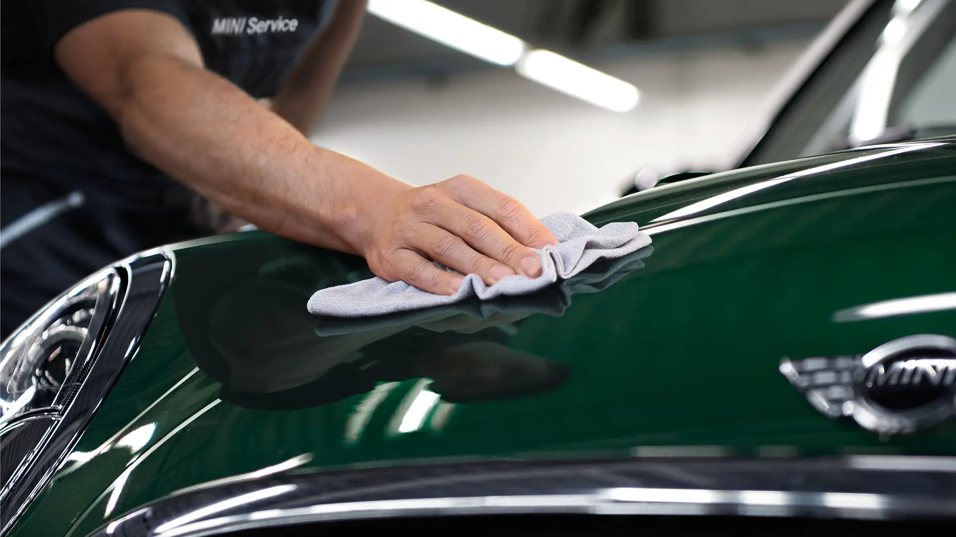 MINI Cleaning and Care – technician polishing MINI Racing Green surface.
