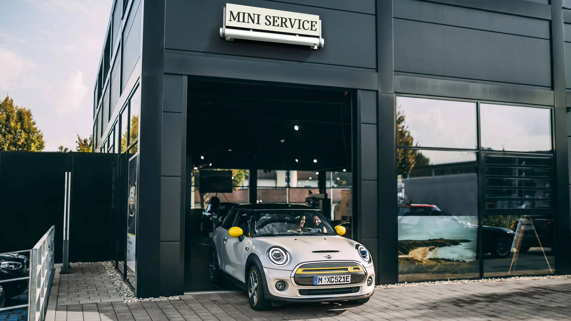 MINI Service Partner premises with a customer driving her new MINI Electric out onto the forecourt
