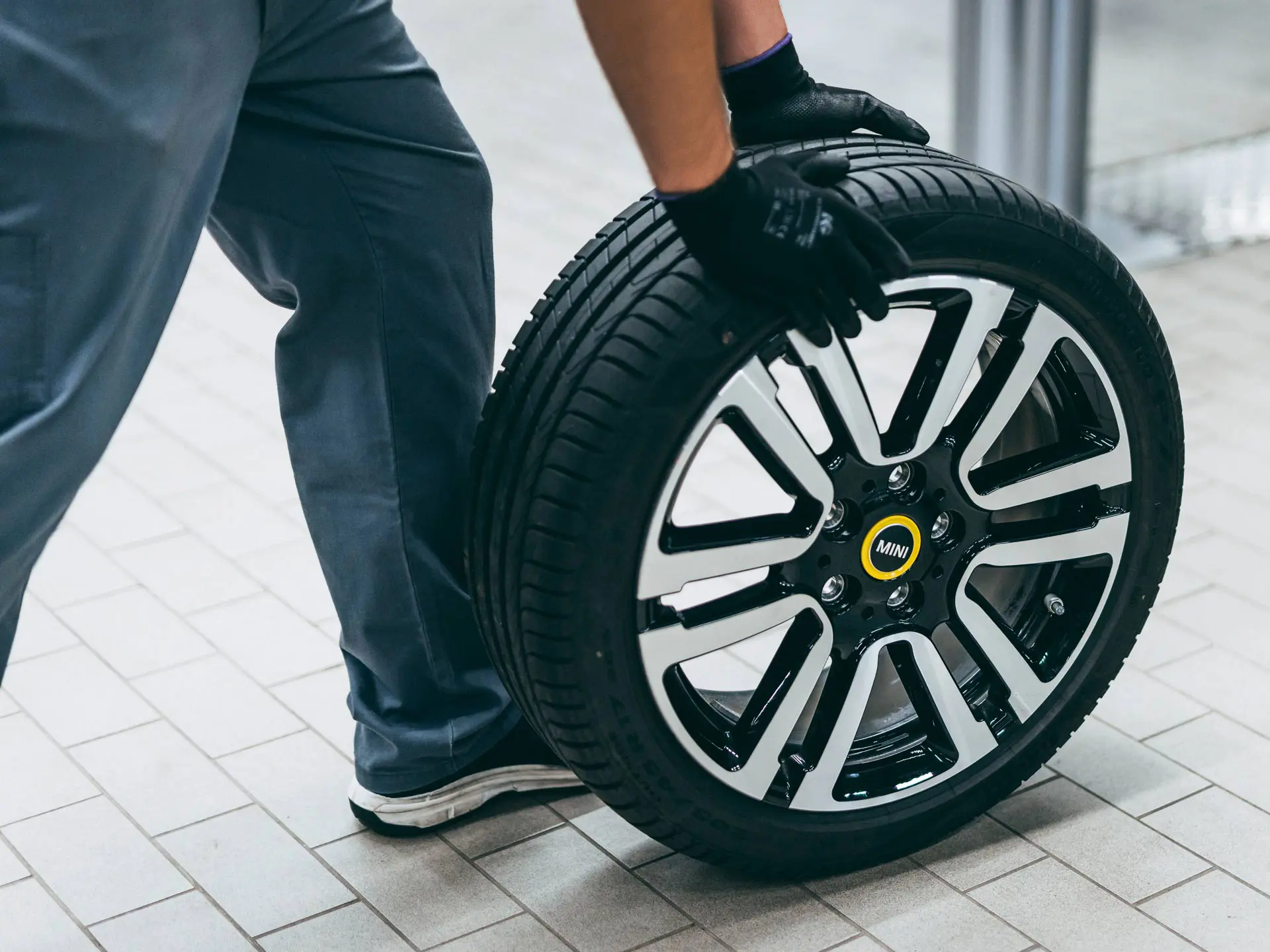 MINI technician rolling a MINI wheel with star-marked tyre in a MINI Service Centre.