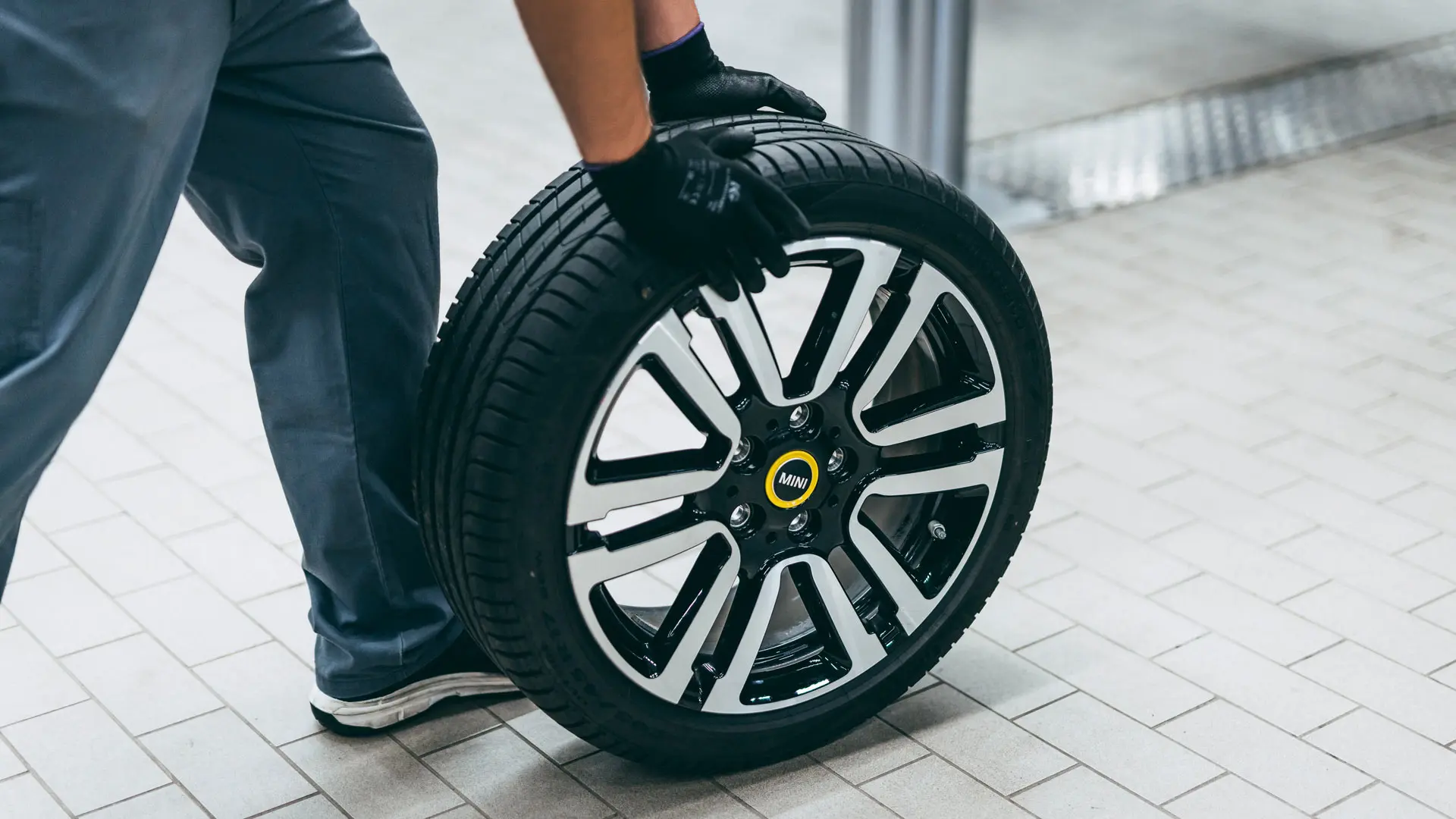 MINI technician rolling a MINI wheel with star-marked tyre in a MINI Service Centre.