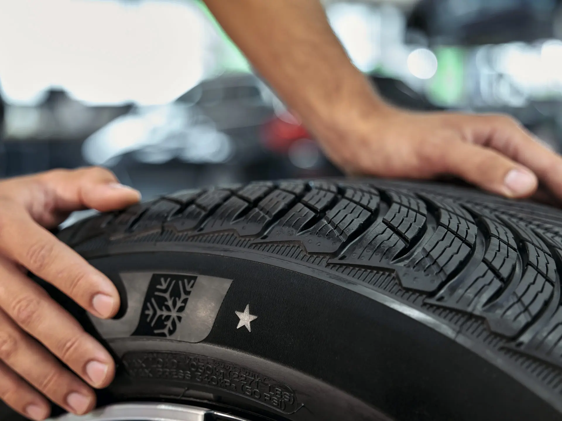 MINI winter wheel with star-marked tyre being rolled into position by a MINI technician in a MINI Service Centre.