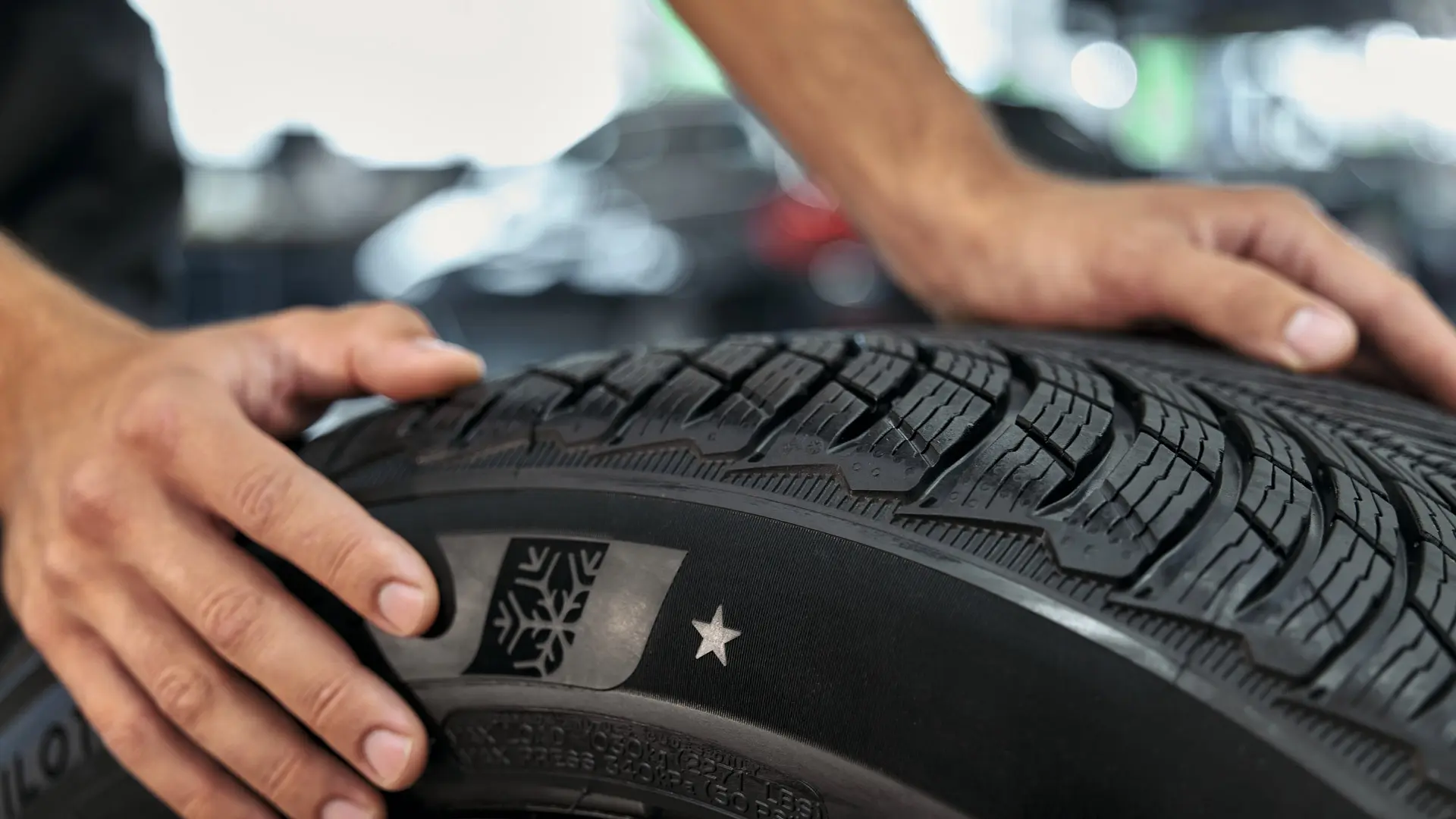 MINI winter wheel with star-marked tyre being rolled into position by a MINI technician in a MINI Service Centre.