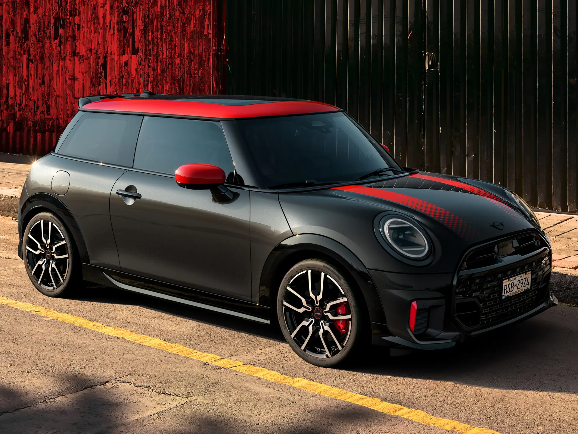 MINI John Cooper Works 3-door in Midnight Black with roof and mirror caps in Chili Red and sport stripes red, side view, parked in street.