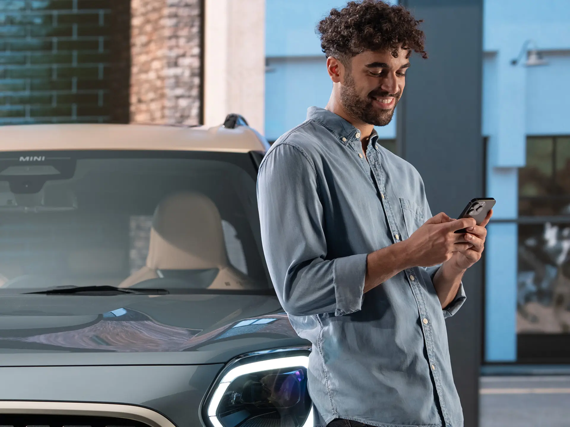 MINI personalised service appointments - a man typing on his phone next to a MINI